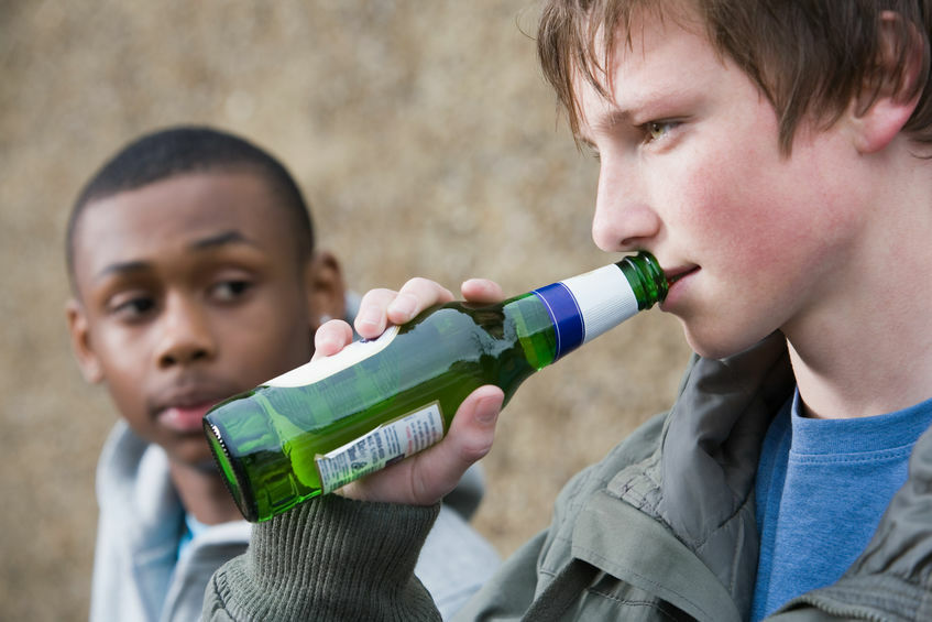 Cropped image of a man giving an alcoholic drink to a teen